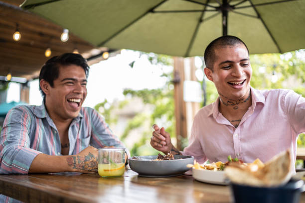 Gay couple eating and having fun at a restaurant Gay couple eating and having fun at a restaurant lgbtqcollection stock pictures, royalty-free photos & images