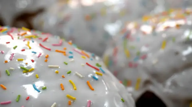 Close-up of glazed easter cakes. Stock footage. Traditional easter cakes covered with white sugar glaze and decorated with rainbow sprinkles.