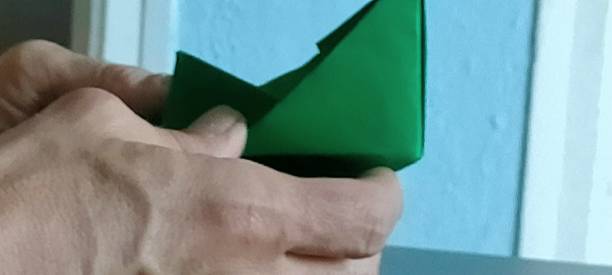 istock Man's hands making a green origami boat.( Origami) 1405285499