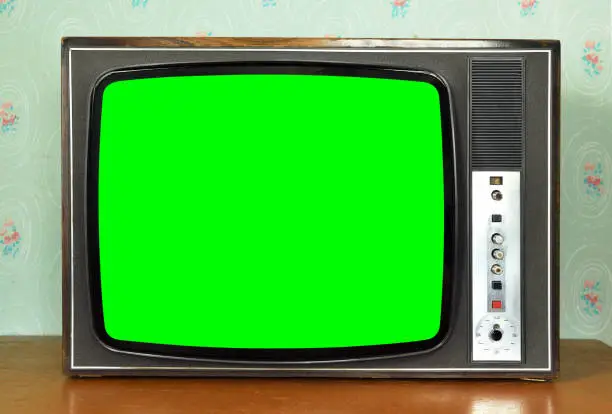 Photo of Old vintage green screen TV in a room with vintage wallpaper. Interior in the style of the 1960s.