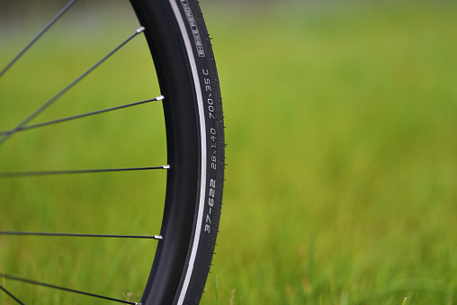 Bicycle wheel is close-up on green grass blurred background. Ecological personal transport concept.