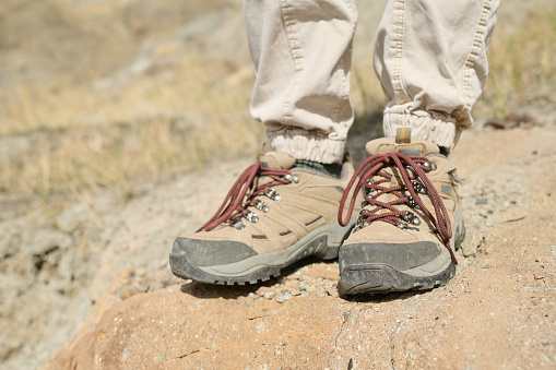 Horizontal close-up of unrecognizable tourist wearing comfortable boots for hiking in mountains