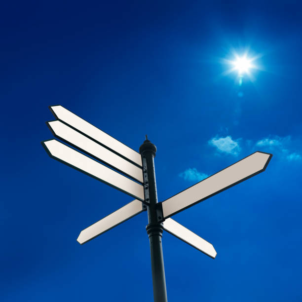 Blank directional signs over sunny blue sky stock photo