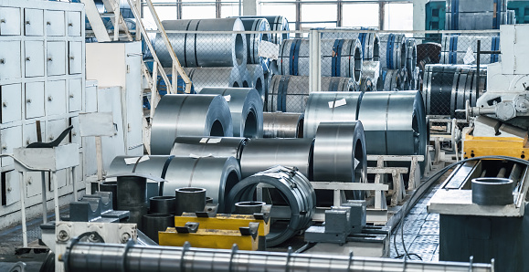 Rolls of galvanized steel sheet in metalworking factory warehouse.