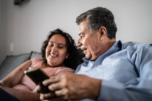 istock Father and psychomotor Intellectual disability daughter using mobile phone at home 1405303812