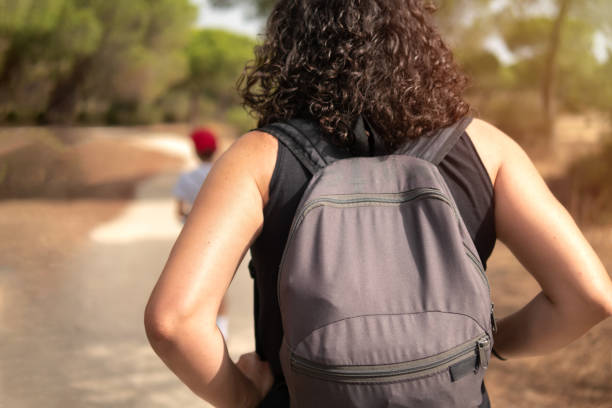istock Woman with rucksack walking along a path through a pine forest. 1405309869