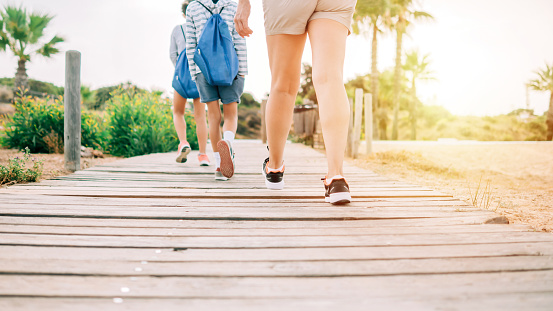 Woman and children walking along a wooden path. Concept of a family walk in nature.