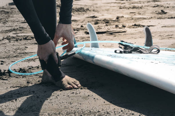 istock Unrecognizable surfer woman attaching surfing leash string to her ankle. 1405330047