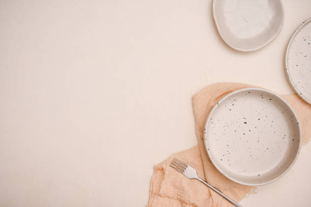 istock Minimal dining table setting with white ceramic plate, bowl, fork, beige napkin and copy space 1405330437