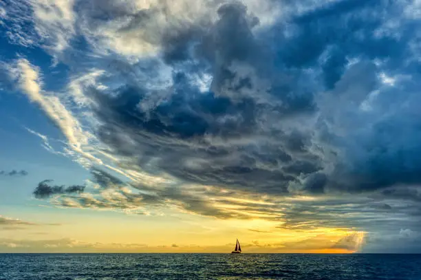 A Storm Is Looming Overhead As A Small Boat Moves Toward The The Shining Light