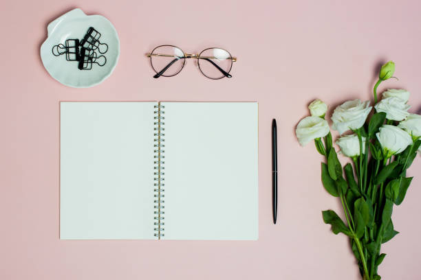 istock White roses with black pen and notebook over the pink background. 1405331937