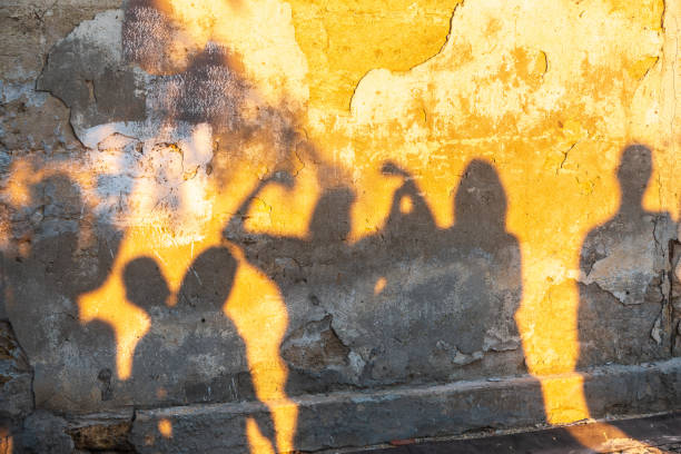 istock Shadows of dancing people on an old stone wall at sunset time. 1405338329