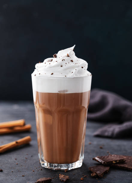 istock Hot chocolate with whipped cream and cinnamon in a tall glass on a dark background. Front view and copy space 1405339999
