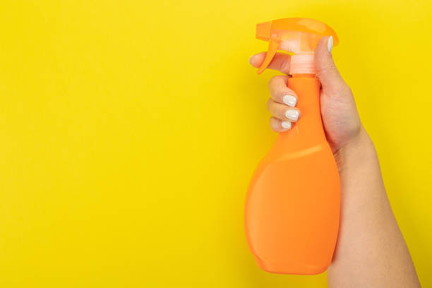 istock Cleaner's hand holding a  chemical spray bottle. Empty space for text or logo on a yellow background. Early spring or regular cleaning. Cleaning and cleaning concept. 1405344592