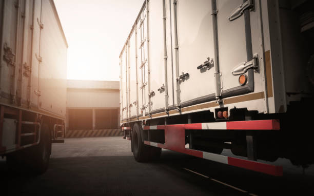 istock Cargo Container Trucks Parked at Distribution Warehouse with the Sunset. Shipping Trucks. Lorry. Cargo Freight Trucks Transport Logistics. 1405348065