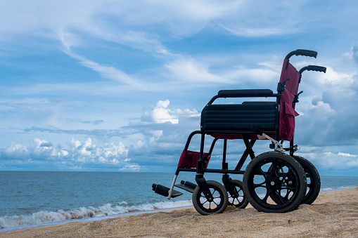 Empty wheelchair parking on sand beach , handicapped traveller concept