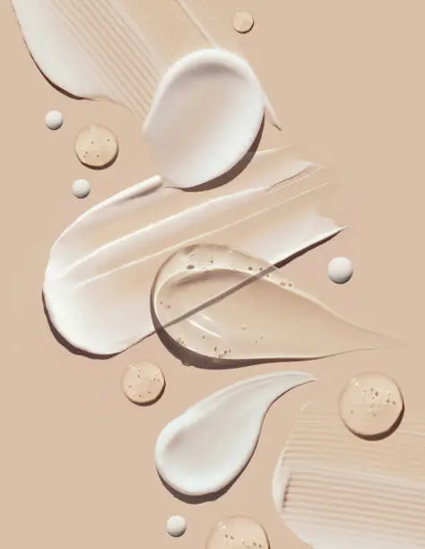 Photo of cosmetic smears of creamy texture on a pastel beige background