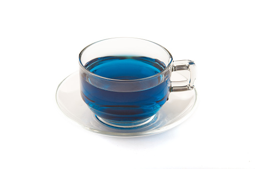 Butterfly pea tea in glass with coaster isolated on white background, blue hot drink.