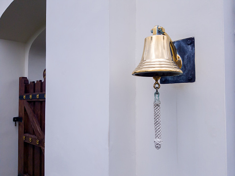 Picture of a golden copper bell hanging on the wall of church area