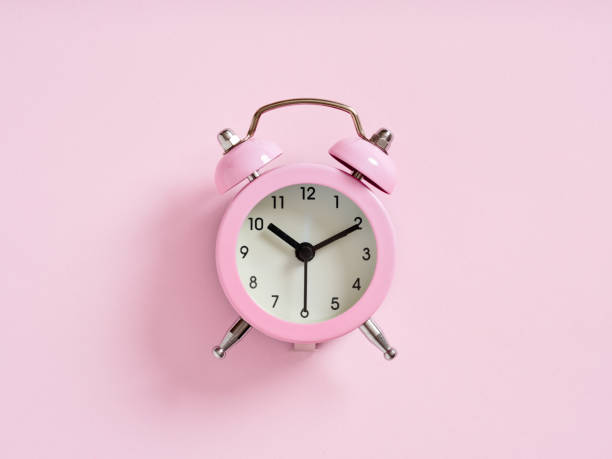 Pink alarm clock on pink background. Close up macro view.