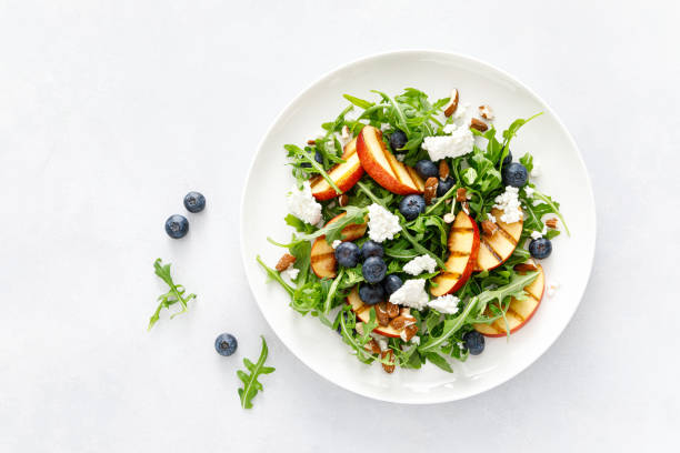 istock Peach, blueberry and arugula fresh fruit salad with cheese and almond nuts, top view 1405357239