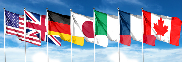 G7 flag. Silk waving flags of G7 countries: Germany, Canada, United States, Italy, France, Japan, United Kingdom. Online Summit. Seven. Isolated on sky background.