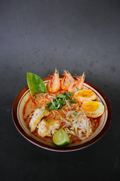 istock laksa, laksa curry made from vermicelli, noodles, bean sprouts, egg, tofu lime, and shrimp with a spicy soup sauce that is rich in spices. laksa served on bowl, isolated on white background. 1405357904