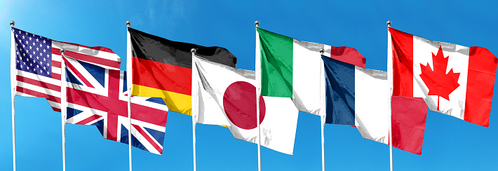 G7 flag. Silk waving flags of G7 countries: Germany, Canada, United States, Italy, France, Japan, United Kingdom. Online Summit. Seven. Isolated on sky background.