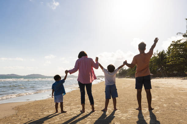 istock back view family holding hands together and having fun on the beach 1405360476