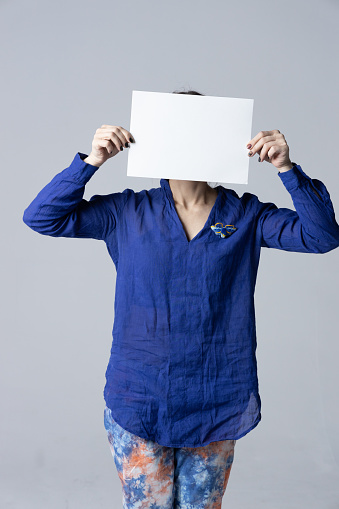 Woman covering her face with a white poster.