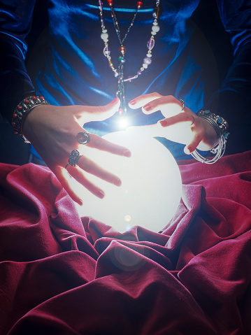 close up on female gypsy hands on a glowing crystal ball