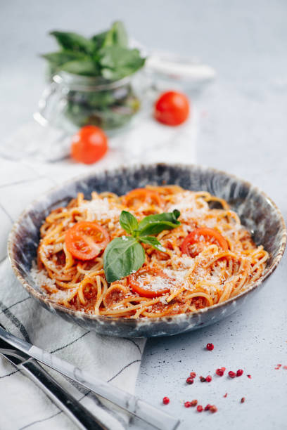 istock Orange pasta with tomatoes and sauce in a plate on a table. 1405363702