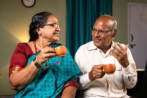Happy senior couple having tea while talking each other at home - concept of happiness, togetherness and retirement lifestyle.