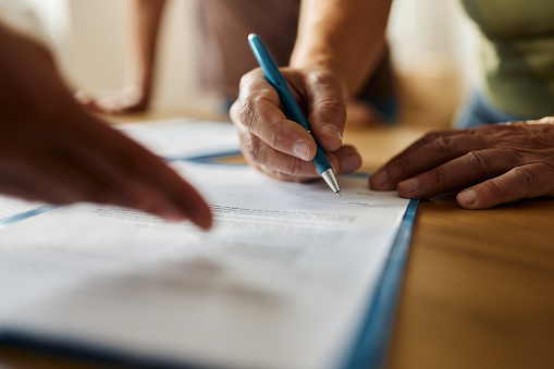 Two Businesspeople Hand Analyzing Document Over Glass Desk