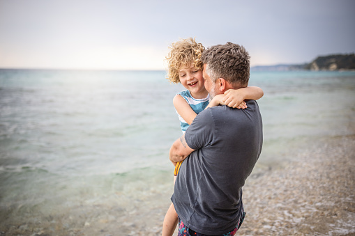 Photo of smiling boy with his father at the beach