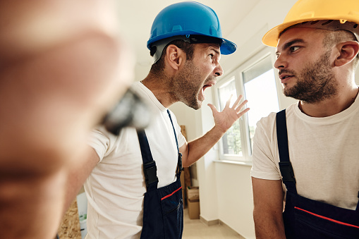 Frustrated worker screaming at his colleague during home renovation process.