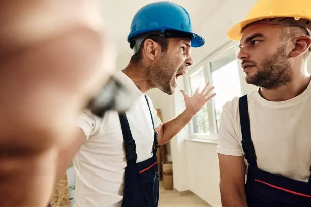 Photo of Frustrated worker screaming at his colleague during home renovation process.