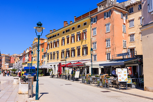 Buildings with sidewalk cafes on the street level downtown in Rovinj, tourists sightseeing