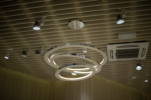 Lamp on ceiling. Designer lighting fixture. Lamps in building. Interior details.