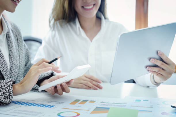 istock two young Asian businesswoman using their tablet computers with calculators and documents to plan marketing strategies and investments to profit from their clients 1405369042