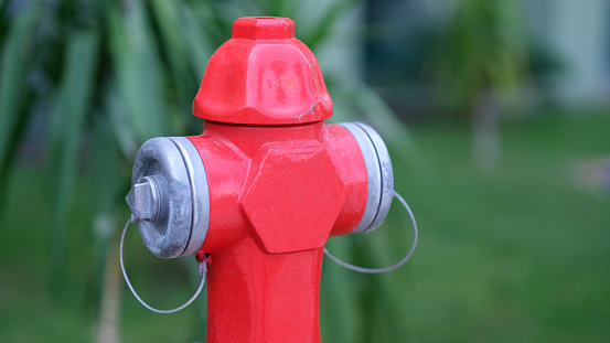 Red fire hydrant standing in park closeup. Fire safety concept