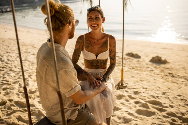 istock Serene couple enjoy the sunset on the beach while swnging on the rope swing 1405374857