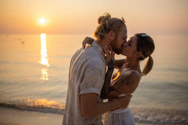 istock Married couple kissing on the beach during sunset 1405375652