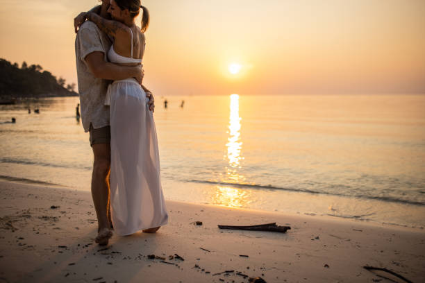 istock Married couple hugging on the beach during sunset 1405375768
