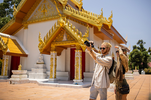 Caucasian couple with camera taking photos of the Thai temple they visiting