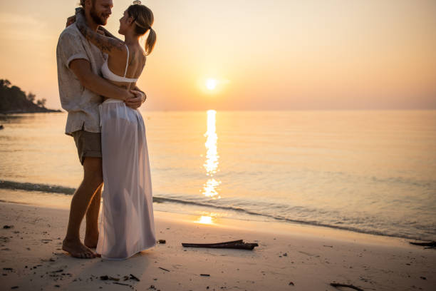 istock Married couple hugging on the beach during sunset 1405375965