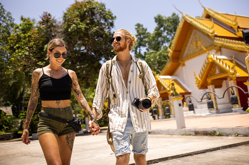 Caucasian couple holding hands, while visiting Thai temple, during their vacation
