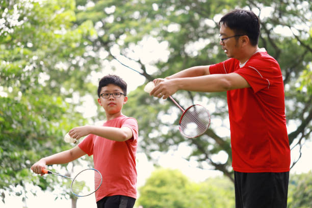 istock Father and son playing badminton in a public park 1405378180