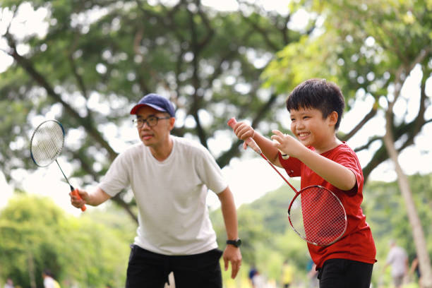 istock Father and son playing badminton in a public park 1405378378