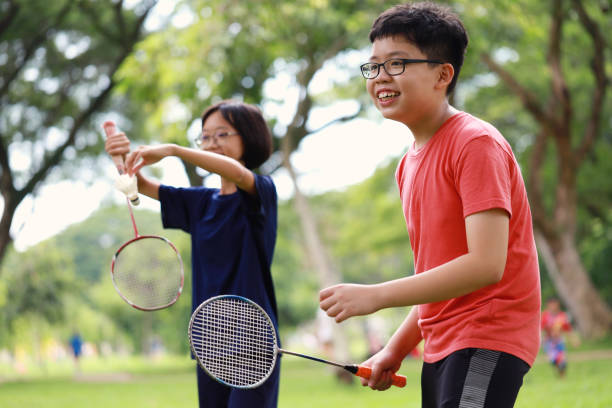 Boy and girl playing badminton in a public park stock photo